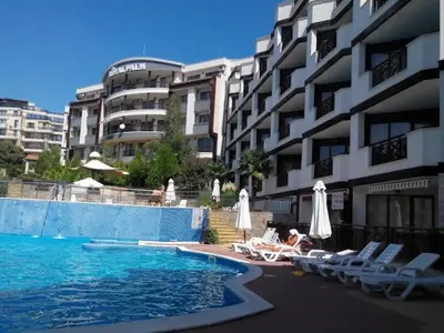 a person laying in chairs next to a swimming pool at ROYAL PALM 84 Studio Sveti Vlas in Sveti Vlas