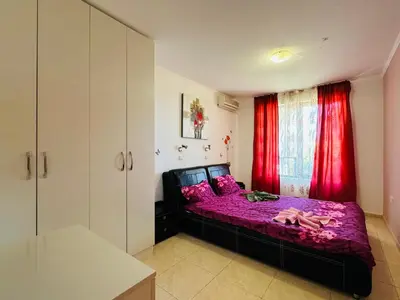 a bedroom with a purple bed with red curtains at VODENICATA 3 Apartament Sveti Vlas in Sveti Vlas