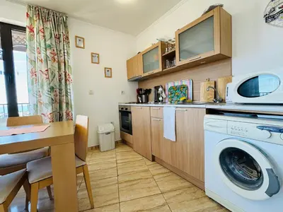 a kitchen with a washing machine and a table at VODENICATA 7 Apartment Sveti Vlas in Sveti Vlas