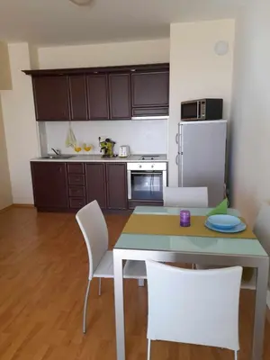 a kitchen with a table and white chairs in a room at Sunrise apartment 2 bedrooms in Obzor