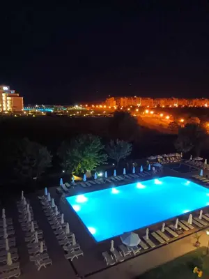 a swimming pool at night with chairs and lights at Sunrise apartment 2 bedrooms in Obzor