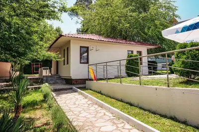 a small house with a balcony and an umbrella at Хотел и Вили Марая in Tsarevo