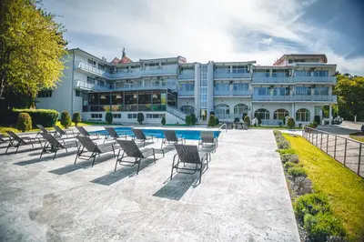 a large building with chairs and a swimming pool at Хотел и Вили Марая in Tsarevo