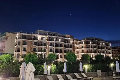 a large building with tables and umbrellas in front of it at DELUXE Beach Apartment in Sveti Vlas in Sveti Vlas