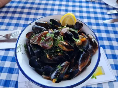 a plate of mussels with a lemon on a table at DELUXE Beach Apartment in Sveti Vlas in Sveti Vlas