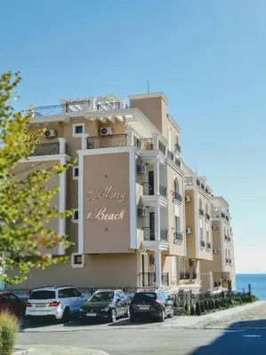 a large building with cars parked in front of it at DELUXE Beach Apartment in Sveti Vlas in Sveti Vlas