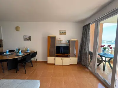a living room with a dining table and a television at Black Pearl Apartment in Sozopol