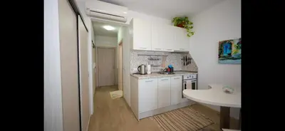 a small kitchen with white cabinets and a sink at Студио Сарафово in Burgas City