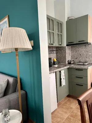 a small kitchen with green cabinets and a table with a lamp at Glarus Apartment with Infinity Sea View in Varna City