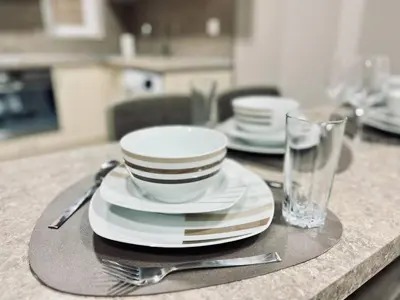 a table with plates and forks and a glass at NJ Deluxe rooms in Varna City