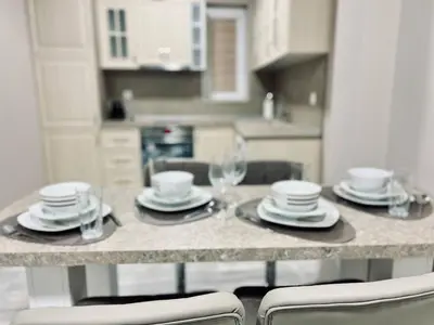 a kitchen with a table with plates and wine glasses at NJ Deluxe rooms in Varna City
