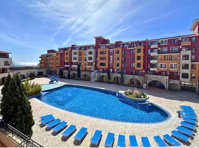 a swimming pool with blue chairs and buildings at Ubytování krásném a klidném prostředí V soukromém apartmánu in Aheloy