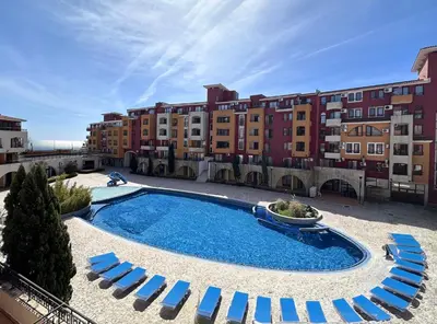 a swimming pool with blue lounge chairs and buildings at Ubytování krásném a klidném prostředí V soukromém apartmánu in Aheloy