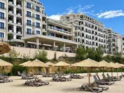 a group of chairs and umbrellas in front of a building at ONYX 1 - Menada Apartments in Sveti Vlas