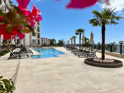 a pool with chairs and palm trees next to a building at ONYX 1 - Menada Apartments in Sveti Vlas