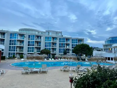 a hotel with a swimming pool and chairs and a building at Sunset Apartment Atlantis Resort in Burgas City