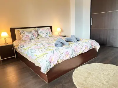 a bedroom with a large bed with a floral bedspread at Lazur Apartment AQUA in Burgas City