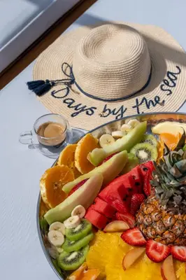 a bowl of fruit with a hat on a table at Sea Twins Luxury Aparthotel - 150 m from the beach in Sunny Beach