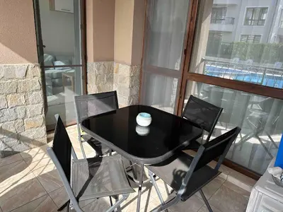 a black dining table and chairs on a balcony at Pool apartment on the beach in Burgas City