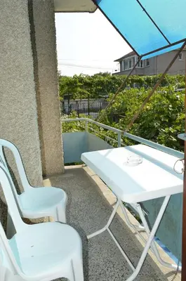 a white table and chairs on a balcony with an umbrella at Лятна вила Генчеви град Обзор in Obzor