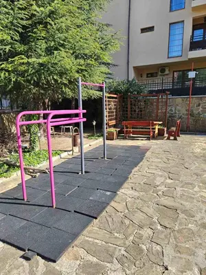 a pink playground equipment on a stone ground at Апатаменти за гости Sunshine и Glory in Sveti Vlas