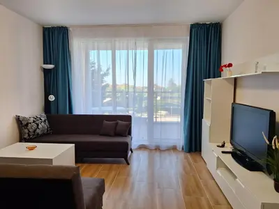 a living room with a couch and a large window at Созополи Хилс A11 in Sozopol