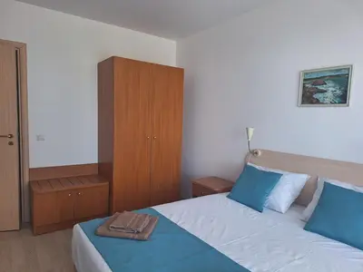 a bedroom with a large bed with blue pillows at Созополи Хилс A11 in Sozopol