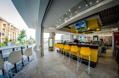 a restaurant with yellow chairs and a bar at Sea view Prestige Fort beach Apartment in Sveti Vlas