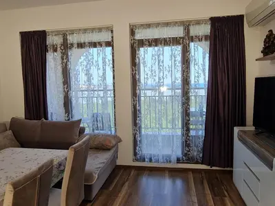 a living room with a couch and two large windows at Луксозен апартамент в Резиденция Лазурен бряг in Burgas City
