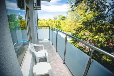 a balcony with two white chairs and trees at Хотел и Вили Марая apartament in Tsarevo