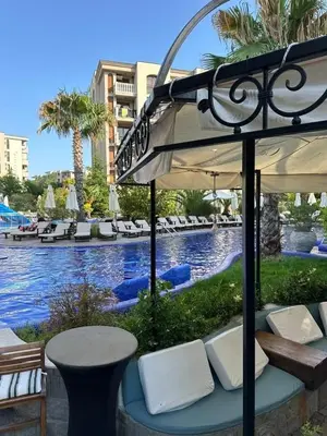 a pool with a table and an umbrella and chairs at Cascadas family apartamant 2 in Sunny Beach