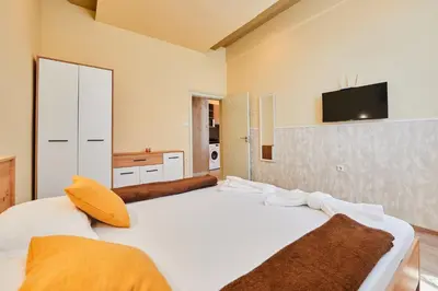 a bedroom with two beds and a tv on the wall at Апартамент Пенека in Pomorie