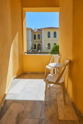a balcony with a table and chairs on a yellow wall at Апартамент Пенека in Pomorie