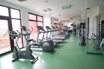 a gym with a row of treadms and elliptical machines at Marina in Aheloy
