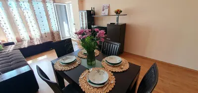 a dining room table with a vase of flowers on it at Sunny Day Pomorie in Pomorie