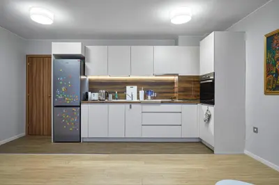 a kitchen with white cabinets and a refrigerator at The little things apt - Parking & Own EV Chаrgеr by Flat Mаnаger in Burgas City