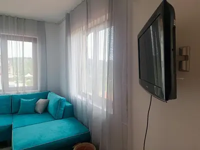 a living room with a blue couch and a flat screen tv at Bulgapart Obzor in Obzor