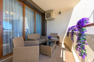 a balcony with wicker chairs and purple flowers at Infinity view 2 Shkorpilovci in Shkorpilovtsi