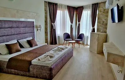 a hotel room with a large bed and two chairs at Амон Ра in Primorsko