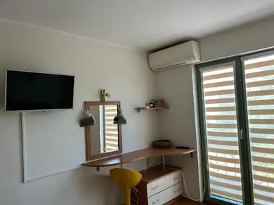 a room with a tv and a mirror and a chair at Nesebar City Apartment in Nesebar