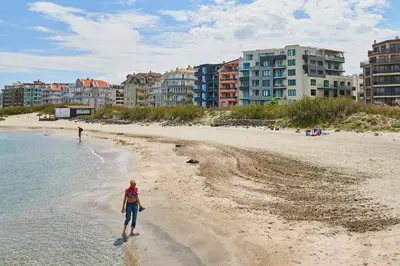 a woman walking on a beach with buildings in the background at Sea view Apartment Pomorie in Pomorie