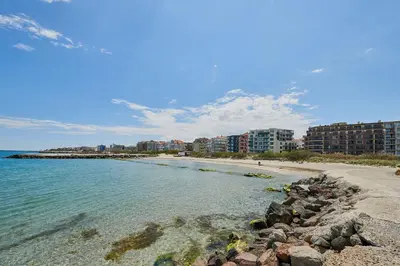 a beach with rocks in the water and buildings at Sea view Apartment Pomorie in Pomorie