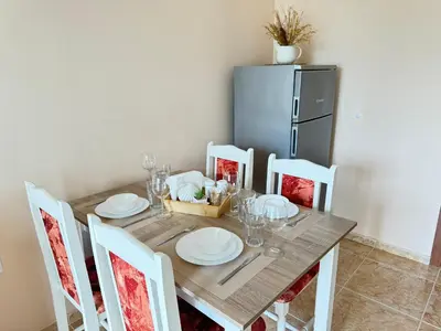a dining room table with white plates and a refrigerator at MaYana Beach Appartament in Burgas City