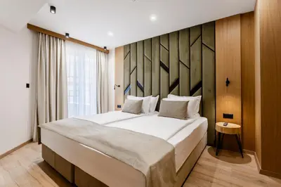 a bedroom with a large bed with a wooden wall at Natura All Seasons Boutique Hotel in Burgas City
