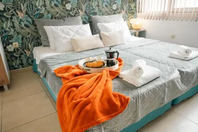 a bed with a tray of food and towels on it at Стилен и уютен апартамент в центъра Варна in Varna City
