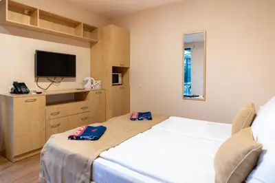 a bedroom with a white bed and a flat screen tv at Private Apartment in PREMIER FORT Beach Aparthotel in Sveti Vlas