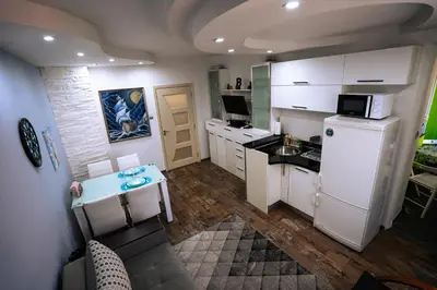 a small kitchen with white cabinets and a refrigerator at Seaside Apartament in Burgas City
