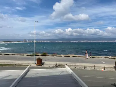 a person standing on a sidewalk next to the ocean at PARADISO 'В' - 107 Panoramic Sea View Large STUDIO Nessebar in Nesebar