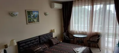 a bedroom with a bed and a table and a window at Семеен Хотел ''Кораб Ренеса'' in Ravda
