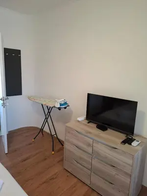a flat screen tv sitting on top of a wooden dresser at LaRenta Стилни апартаменти с 2 спални и гледка море в Свети Влас in Sveti Vlas